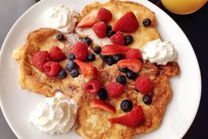 picture of apple pancakes with fresh fruit and whipped cream